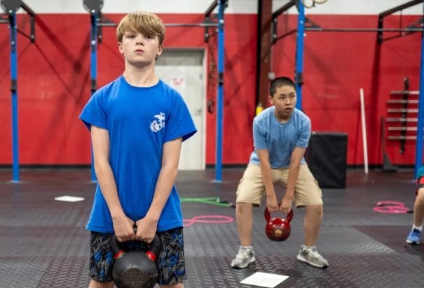 two boys hold kettlebell