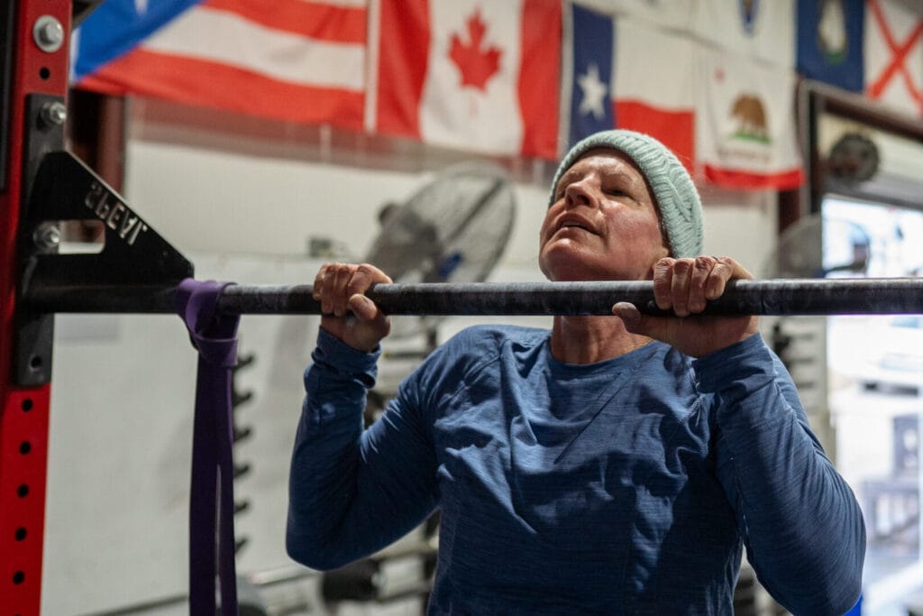 Older woman performing pull-up at Fit Augusta gym, demonstrating functional strength that matters more than ideal weight